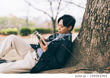 木にもたれて本を読む男性 木にもたれて本を読む男性 109964969