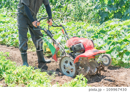 畑を小型トラクターで耕す農家のアジア人男性（農業・田舎暮らし） 109967430