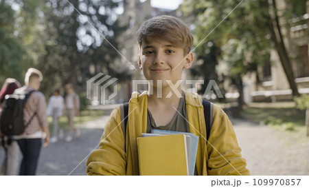 Nice middle school boy smiling on camera, holding books, ready for classes Nice middle school boy smiling on camera, holding books, ready for classes 109970857