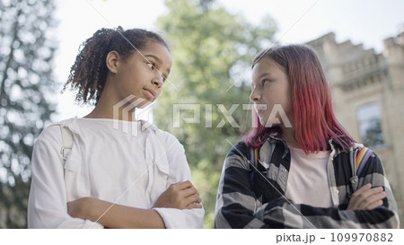 Two girls looking at each other with hostility, bullying, socialization problem at school 109970882