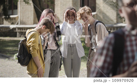 Group of school children gossiping and laughing at insecure classmate, bullying Group of school children gossiping and laughing at insecure classmate, bullying 109970920