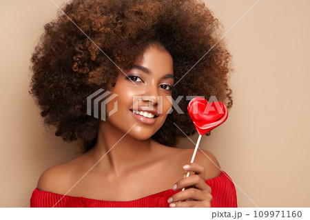 Beautiful portrait of an African girl with a heart shaped lollipop 109971160