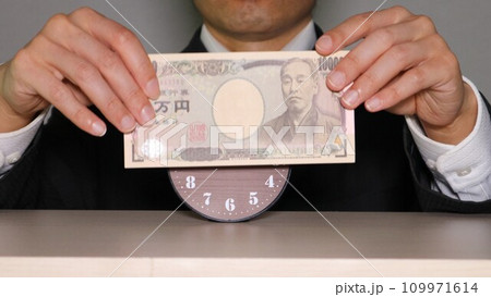 時計の前で紙幣を持つビジネスマン 109971614