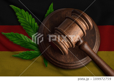 Flag of Germany and justice wooden gavel with cannabis leaf. Illegal growth of cannabis plant and drugs spreading. Flag of Germany and justice wooden gavel with cannabis leaf. Illegal growth of cannabis plant and drugs spreading. 109972759