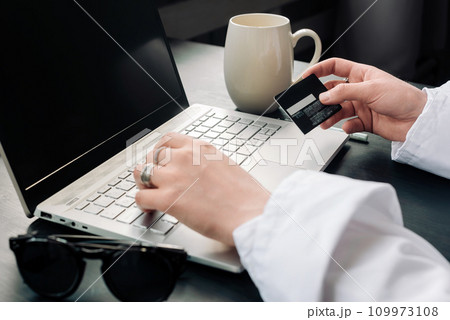 Elegant Woman's Hands Shopping Online with Laptop and Credit Card. Effortless Online Shopping Elegant Woman's Hands Shopping Online with Laptop and Credit Card. Effortless Online Shopping 109973108