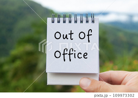 Hand holding notepad with Out Of Office text with nature background 109973302