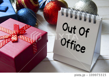 Out of office text on notepad with Christmas decoration. Holiday concept Out of office text on notepad with Christmas decoration. Holiday concept 109973315