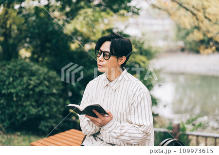 公園で本を読む男性 109973615