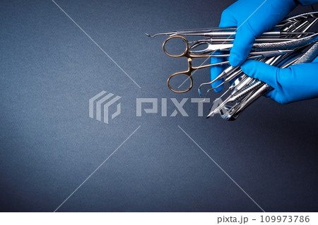 Hands in blue gloves holding metal dental equipment 109973786