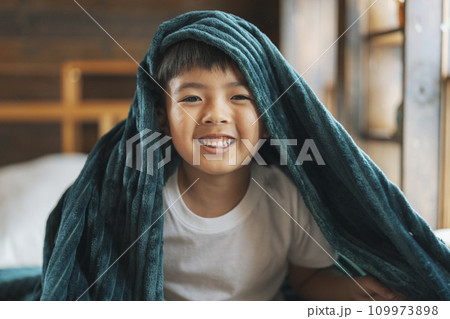 毛布を被ったカメラ目線で笑顔の男の子　 109973898