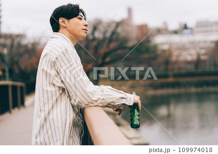 屋外でお酒を飲む男性 109974018