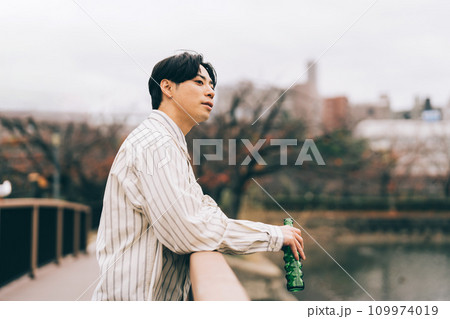屋外でお酒を飲む男性 109974019