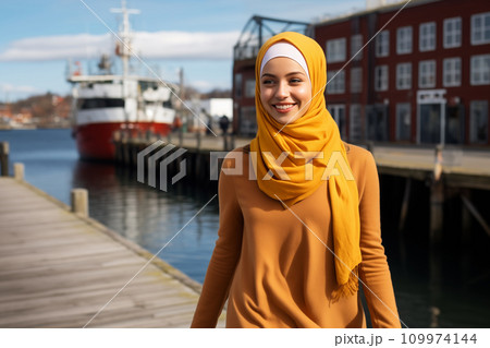 Attractive Muslim woman in yellow hijab walks along the pier 109974144