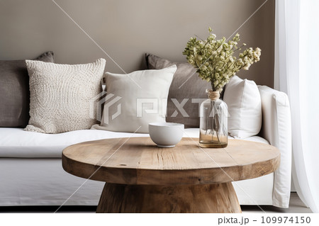 Minimal living room with Round wooden coffee table near sofa close-up. Natural interior decor and biophilic design Minimal living room with Round wooden coffee table near sofa close-up. Natural interior decor and biophilic design 109974150