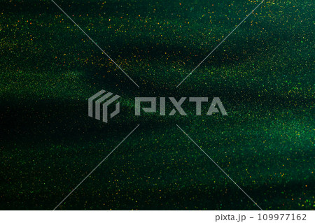 Glittering flows of gold particles in green fluid. Various stains and overflows of gold particles in liquid. Abstract shimmering background with flows of golden glitters dust. Glittering flows of gold particles in green fluid. Various stains and overflows of gold particles in liquid. Abstract shimmering background with flows of golden glitters dust. 109977162