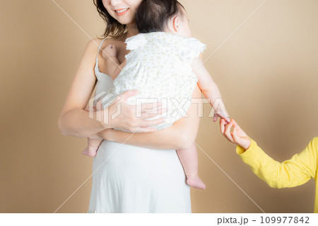 赤ちゃんを抱く女性と小学生の女の子の手 109977842