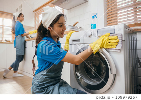 Woman hand in protective glove cleans and wipes washing machine. Highlighting regular housework and hygiene routine. Cleaner working glove house purity. Clean technology. Maid Cleaning service. Woman hand in protective glove cleans and wipes washing machine. Highlighting regular housework and hygiene routine. Cleaner working glove house purity. Clean technology. Maid Cleaning service. 109979267