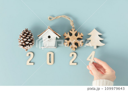 Close up image of hand folds wooden numbers into the number of the new year 2024 109979643