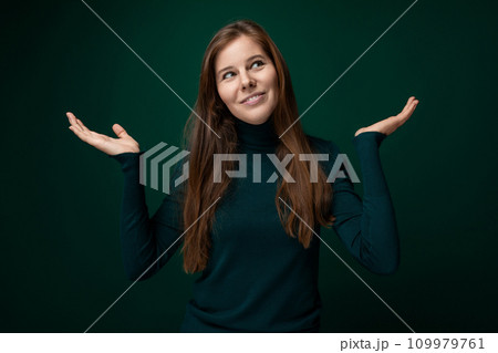 Caucasian young woman wearing a green turtleneck on a dark background with copy space 109979761