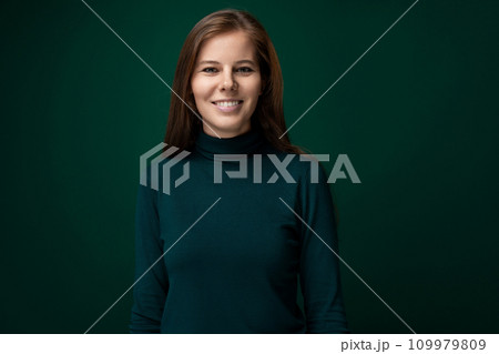 Charming young woman with long brown hair on dark green background 109979809