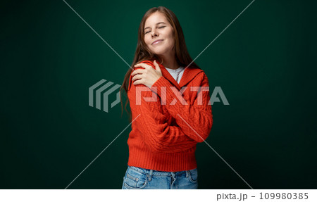 Smiling young woman with brown straight hair wearing a red sweater on a green background with copy Smiling young woman with brown straight hair wearing a red sweater on a green background with copy 109980385
