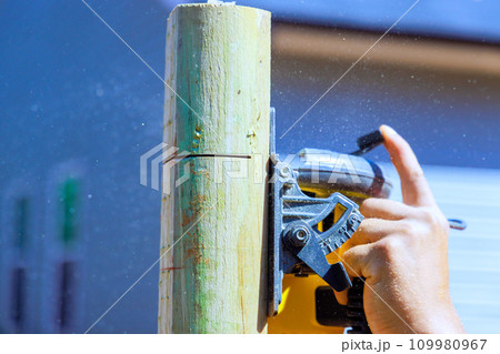 Working on installation of fence post by cutting it with using an electric saw Working on installation of fence post by cutting it with using an electric saw 109980967