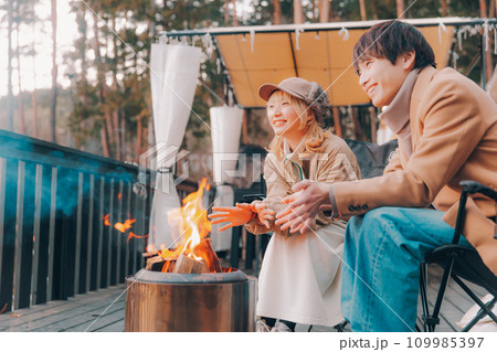 キャンプ場で焚き火をしているカップル キャンプ場で焚き火をしているカップル 109985397
