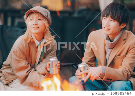 キャンプ場で焚き火をして乾杯をしているカップル キャンプ場で焚き火をして乾杯をしているカップル 109985464