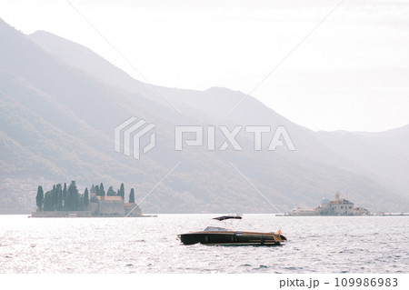 Black motor yacht sails past the island of St. George in the Bay of Kotor. Montenegro 109986983