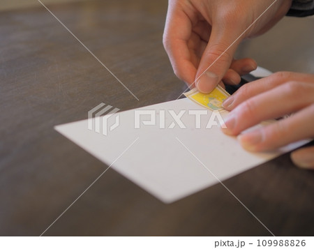 ハガキに切手を貼る男性の手 109988826