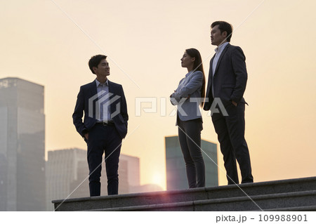 team of asian corporate executives standing on a platform chatting talking conversing at dusk team of asian corporate executives standing on a platform chatting talking conversing at dusk 109988901