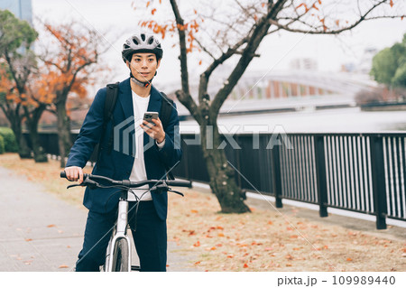 自転車を止めてスマホを見るビジネスマン 109989440