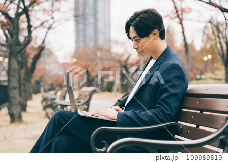 公園のベンチでパソコンを使う男性 109989819