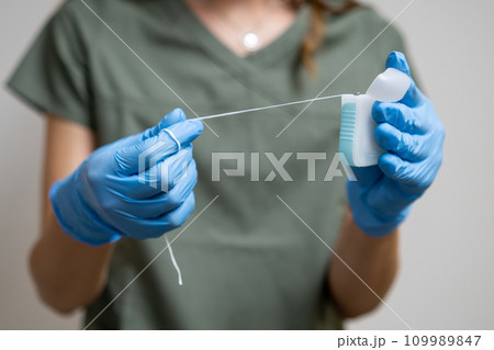 Oral floss manipulated by a dental practitioner wearing rubber gloves Oral floss manipulated by a dental practitioner wearing rubber gloves 109989847