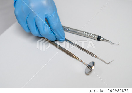 Close up dentist hand takes dental hook from the table. Close up dentist hand takes dental hook from the table. 109989872