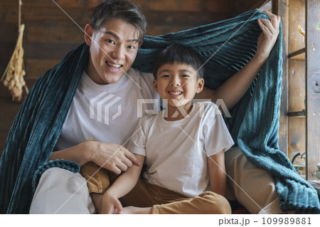 ベッドの上で毛布にくるまった笑顔の親子　 109989881