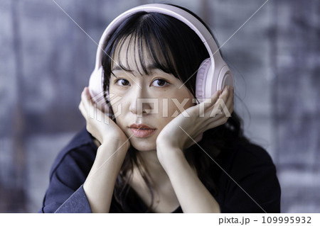 ヘッドホンで音楽を聴く若い女性 109995932