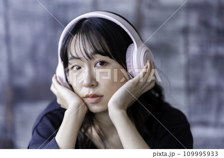 ヘッドホンで音楽を聴く若い女性 109995933