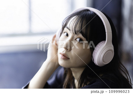 ヘッドホンで音楽を聴く若い女性 109996023