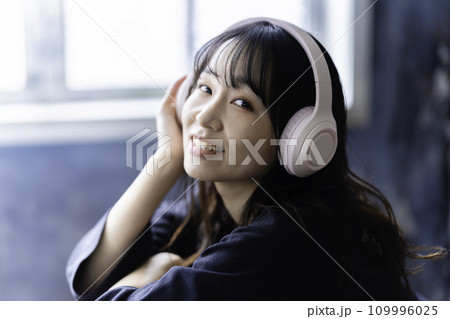 ヘッドホンで音楽を聴く若い女性 109996025