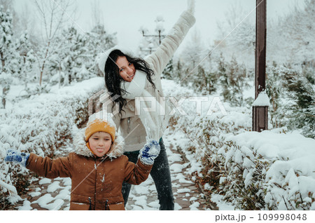 Happy funny moms with child boy son playing in park in the snow 109998048