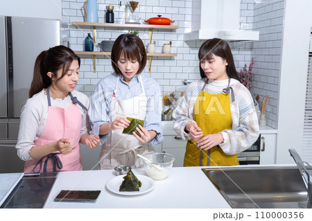 キッチンでおにぎりを作る3人の女性 110000356