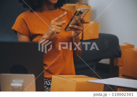 Startup SME small business entrepreneur of freelance Asian woman using a laptop with box Cheerful success happy Asian woman her hand lifts up online marketing packaging and delivery SME idea concept 110002301
