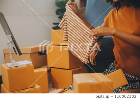 Startup SME small business entrepreneur of freelance Asian woman using a laptop with box Cheerful success happy Asian woman her hand lifts up online marketing packaging and delivery SME idea concept 110002302