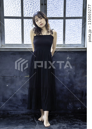 シックな部屋で黒ワンピースを着た若い女性 110003277