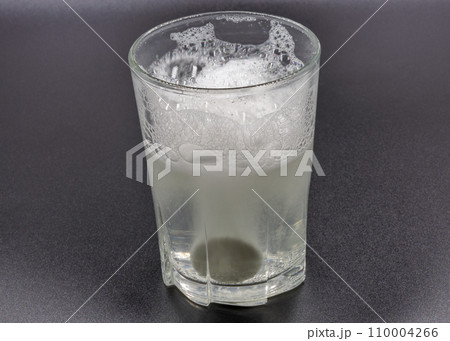 Dissolving instant effervescent tablets in a glass of water closeup 110004266