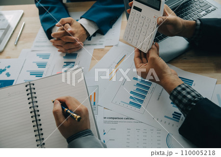 Financial analysts analyze business financial reports on a digital tablet planning investment project during a discussion at a meeting of corporate showing the results of their successful teamwork. 110005218