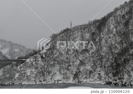 雪に覆われた冬の寒い日の長井ダムの山の風景 110006120