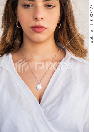 Young woman wearing a silver chain pearl necklace and silver earrings. Young woman wearing a silver chain pearl necklace and silver earrings. 110007427