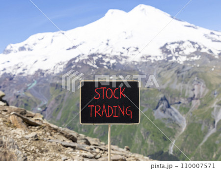 Stock trading symbol. Concept words Stock trading on beautiful black chalk blackboard. Beautiful mountain Elbrus blue sky background. Business stock trading concept. Copy space. 110007571